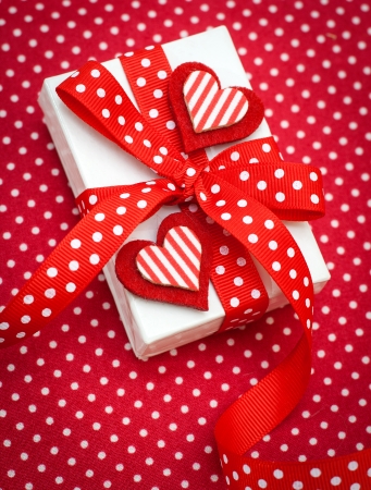 White gift box with red ribbon on red backgroundの写真素材