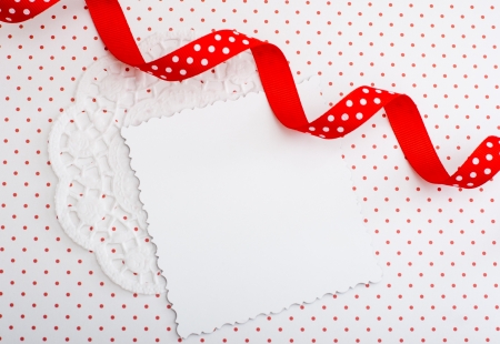 White decorative card on a red and white background with a ribbonの写真素材