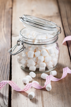 Sweet marshmallow in a glass jar on a wooden tableの写真素材
