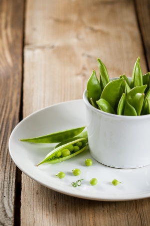 Pods of green peas in white bowlの写真素材