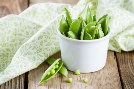 Pods of green peas in white bowlの写真素材