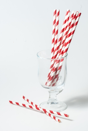 Striped straws for cocktails in a glass on a white backgroundの写真素材