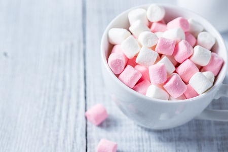 Pink and white marshmallows in a cup, over wood background.の写真素材