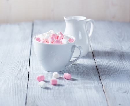 Pink and white marshmallows in a cup, over wood background.の写真素材