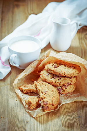 Cookies with chocolate chips in a white plate and a cup of milkの写真素材