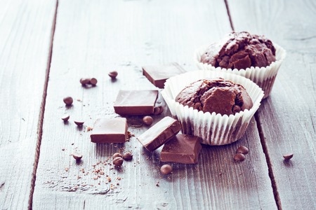 Chocolate muffins decorated with mint leaves and chocolate chips on a wooden tableの写真素材
