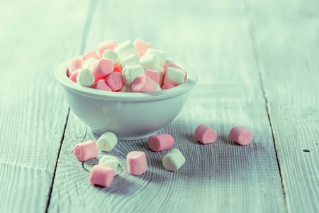 Pink and white marshmallows in bowl, over wood background.の写真素材