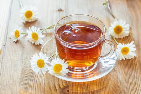 Cup of tea with chamomile flowers on rustic wooden backgroundの写真素材