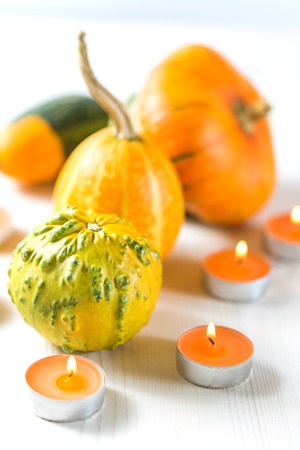 Decorative small pumpkins and candles on white wooden backgroundの写真素材