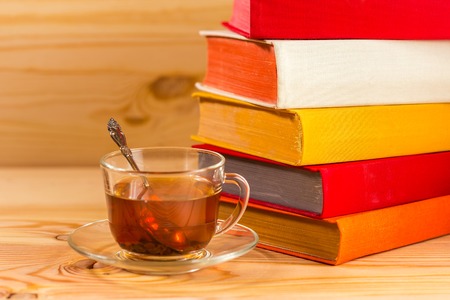 The glass cup and colorful books on wooden backgroundの写真素材