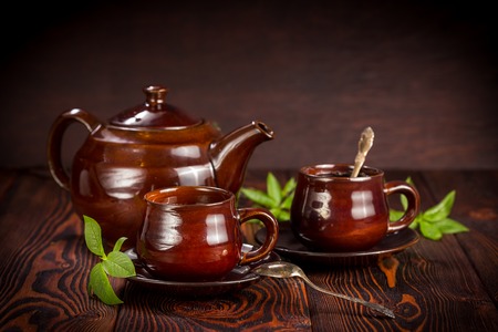 Brown ceramic teapot and two cups of tea on rustic wooden tableの写真素材