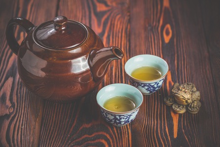 Broun ceramic teapot and two cups for the tea ceremony on rustic wooden tableの写真素材