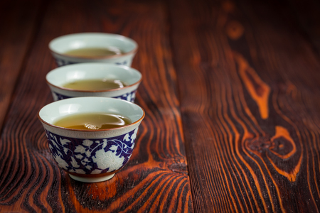 Three Chinese porcelain cup with green tea on a dark wooden backgroundの写真素材