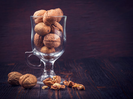 Walnut kernels and whole walnuts in a glass on a dark old wooden table