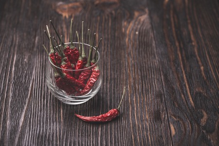 Dry red hot chili peppers in a glass on wooden dark backgroundの写真素材