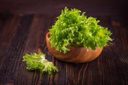 Green cucumbers and salad leaves on a wooden background