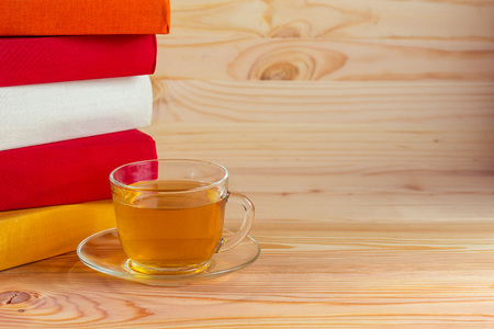 The glass cup and colorful books on wooden backgroundの写真素材