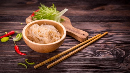 Ingredients of Asian cuisine - rice noodles, leek, lettuce, red hot pepper on a dark wooden backgroundの写真素材