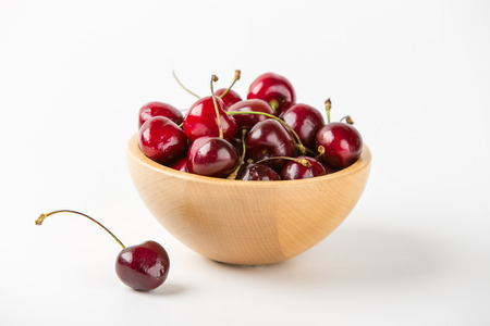 Sweet cherry berries in wooden bowl isolated on white backgroundの写真素材