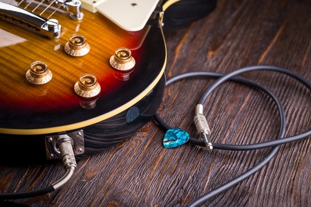 Electric guitar guitar connected with a cable on wooden table close upの写真素材