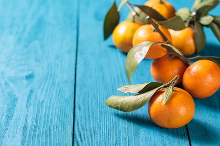 Tangerines with leaves on blue wooden table.の写真素材