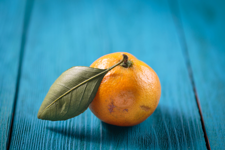 Tangerines with leaves on blue wooden table.の写真素材