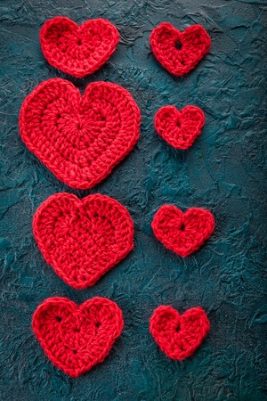 Red crochet valentine hearts on dark bacground.の写真素材