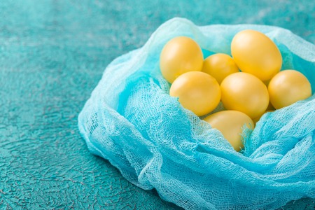 Yellow Easter eggs on a turquoise backgroundの写真素材