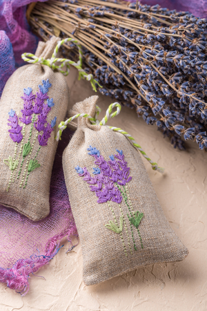 Two aromatic embroidered sachets filled with dried lavender and a bouquet of dry lavenderの写真素材