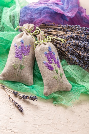 Two aromatic embroidered sachets filled with dried lavender and a bouquet of dry lavenderの写真素材