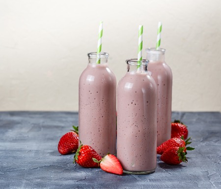 Strawberry-banana smoothie in three bottles on blue backgroundの写真素材