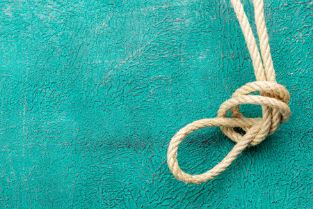 Ship rope knot on turquoise background. Top view. Place for text.