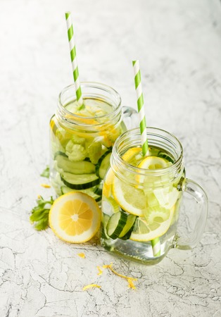 Detox infused hydrating water with cucumber, lemon and celery in glass jars on a light backgroundの写真素材