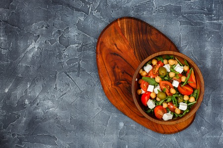 Spring vegetable salad with arugula, cherry tomatoes, chickpeas, olives and feta cheese. Top view. Place for text.の写真素材
