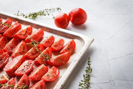 Dried tomatoes in baking tray and spatula on blue wooden backgroundの写真素材