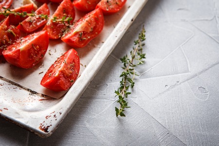 Dried tomatoes in baking tray and spatula on blue wooden backgroundの写真素材