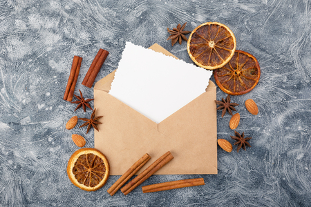 Envelope with greeting card and spices - cinnamon, anise stars, dried oranges and almonds. Flat lay. Top viewの写真素材