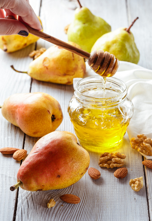 Tasty pears with honey and nuts on wooden tableの写真素材
