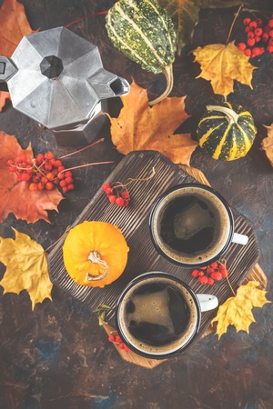 Autumn still life with enamel cups with coffee, pumpkins and maple leaves. Top view. Top viewの写真素材
