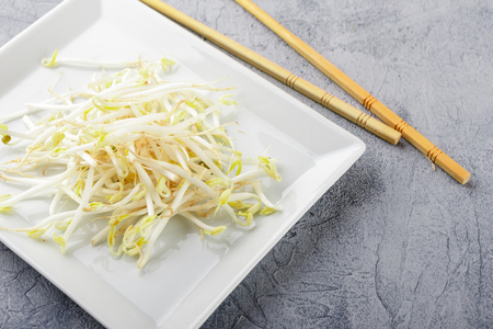 Fresh bean sprouts on white square plate and chopsticks. Concept of healthy foods, vegetarian food.の写真素材