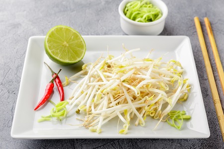 Fresh bean sprouts on white square plate and chopsticks. Concept of healthy foods, vegetarian food.の写真素材