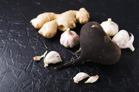 Tuber black radish and garlic on a black concrete backgroundの写真素材