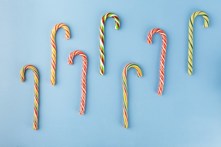 Sweet Candy canes on blue background. Flat lay. Top view.の写真素材