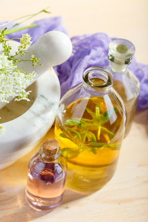 Mortar with fresh wild flowers and essential oil in glass bottlesの写真素材