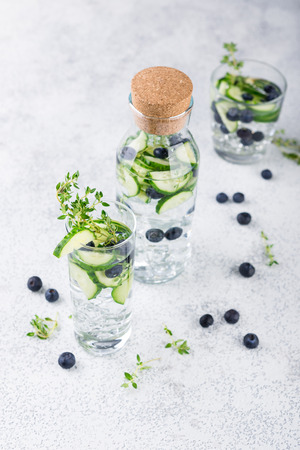 Detox infused flavored water with blueberry, cucumber and thyme on white background. Refreshing summer homemade cocktailの写真素材