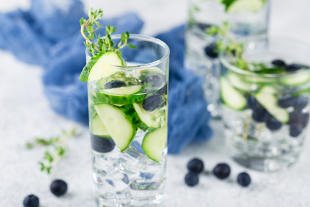 Detox infused flavored water with blueberry, cucumber and thyme on white background. Refreshing summer homemade cocktailの写真素材