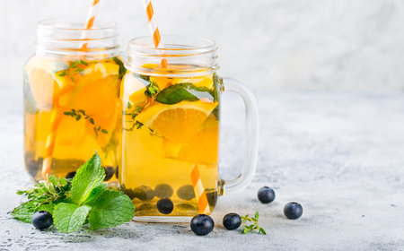 Orange Blueberry Detox Water or lemonade with mint in glass jar on ligth tableの写真素材