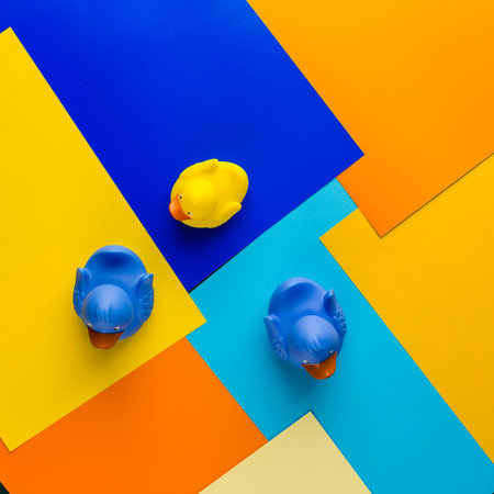 Yellow and blue rubber ducks on multicolored background. Top view