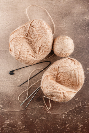 Hanks of woolen brown threads, knitting needles and a knitting pattern on a brown backgroundの写真素材