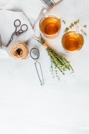 Transparent glasses cup of herbal tea with thyme and sprigs of thyme tied in a bunch on a white background. Top view. Space for text.の写真素材
